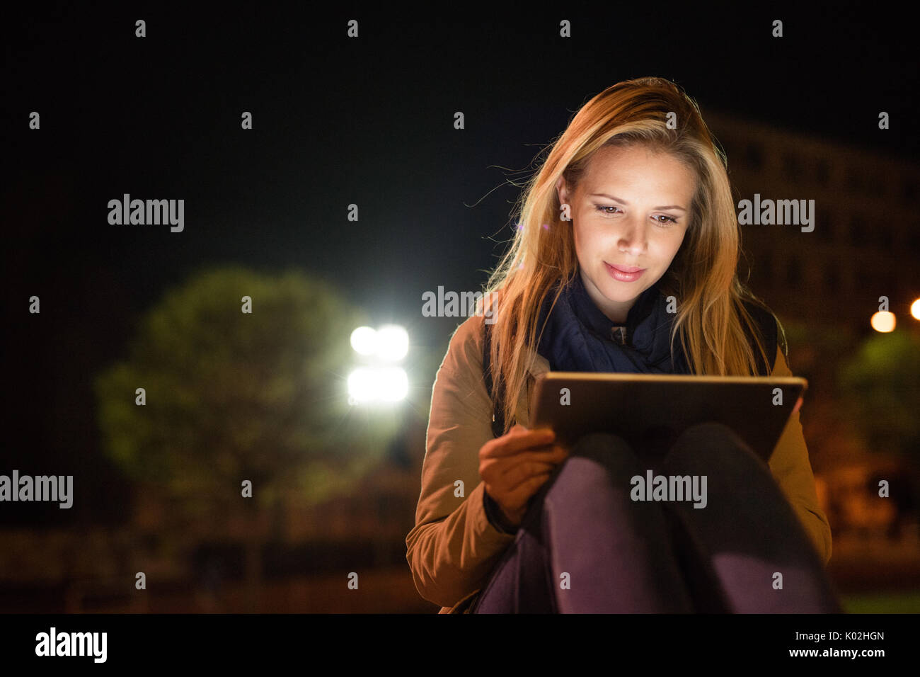 Femme dans la ville la nuit holding tablet, lire quelque chose. Banque D'Images