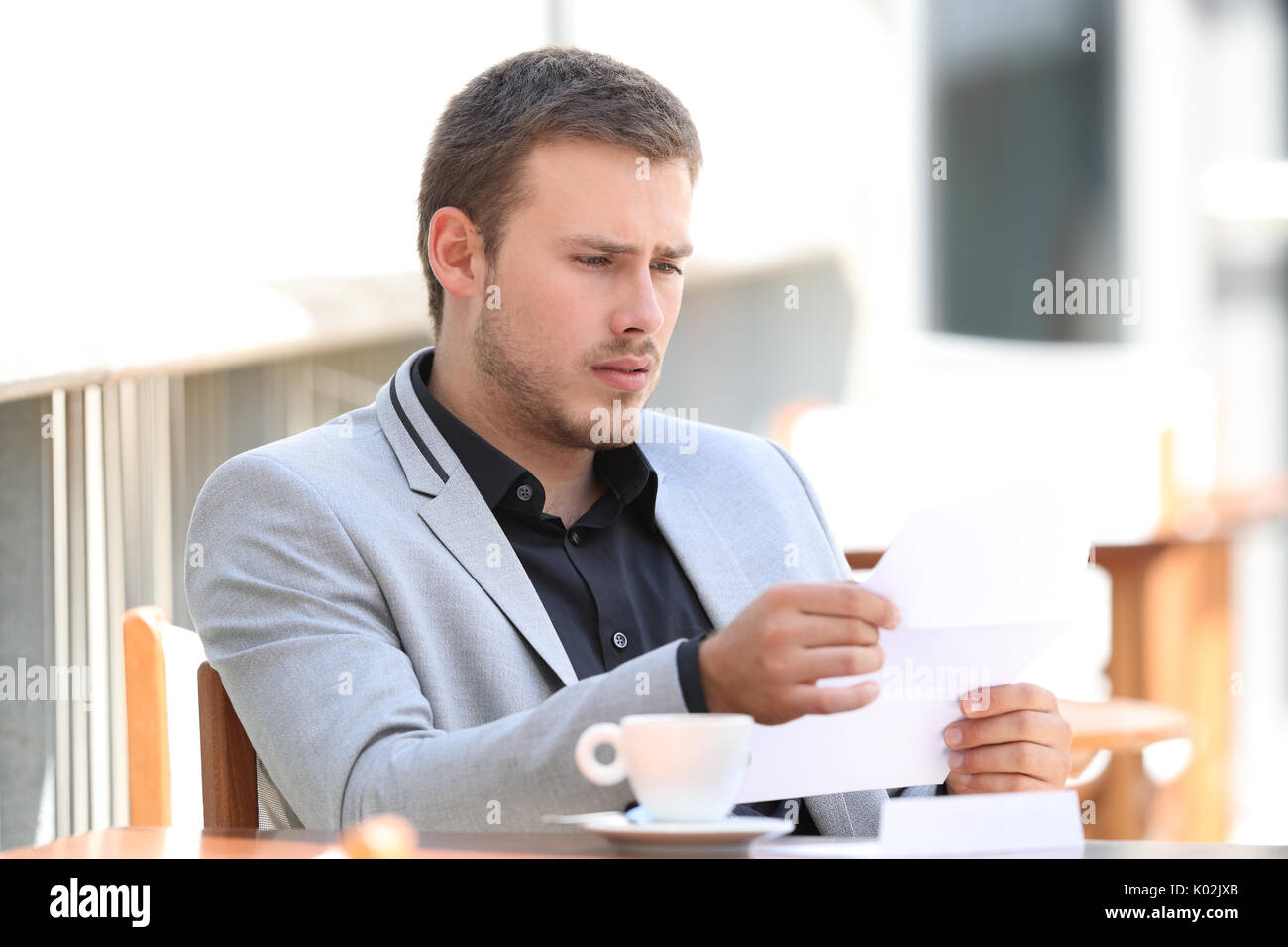 Triste lecture exécutif de mauvaises nouvelles dans une lettre assis dans un café Banque D'Images
