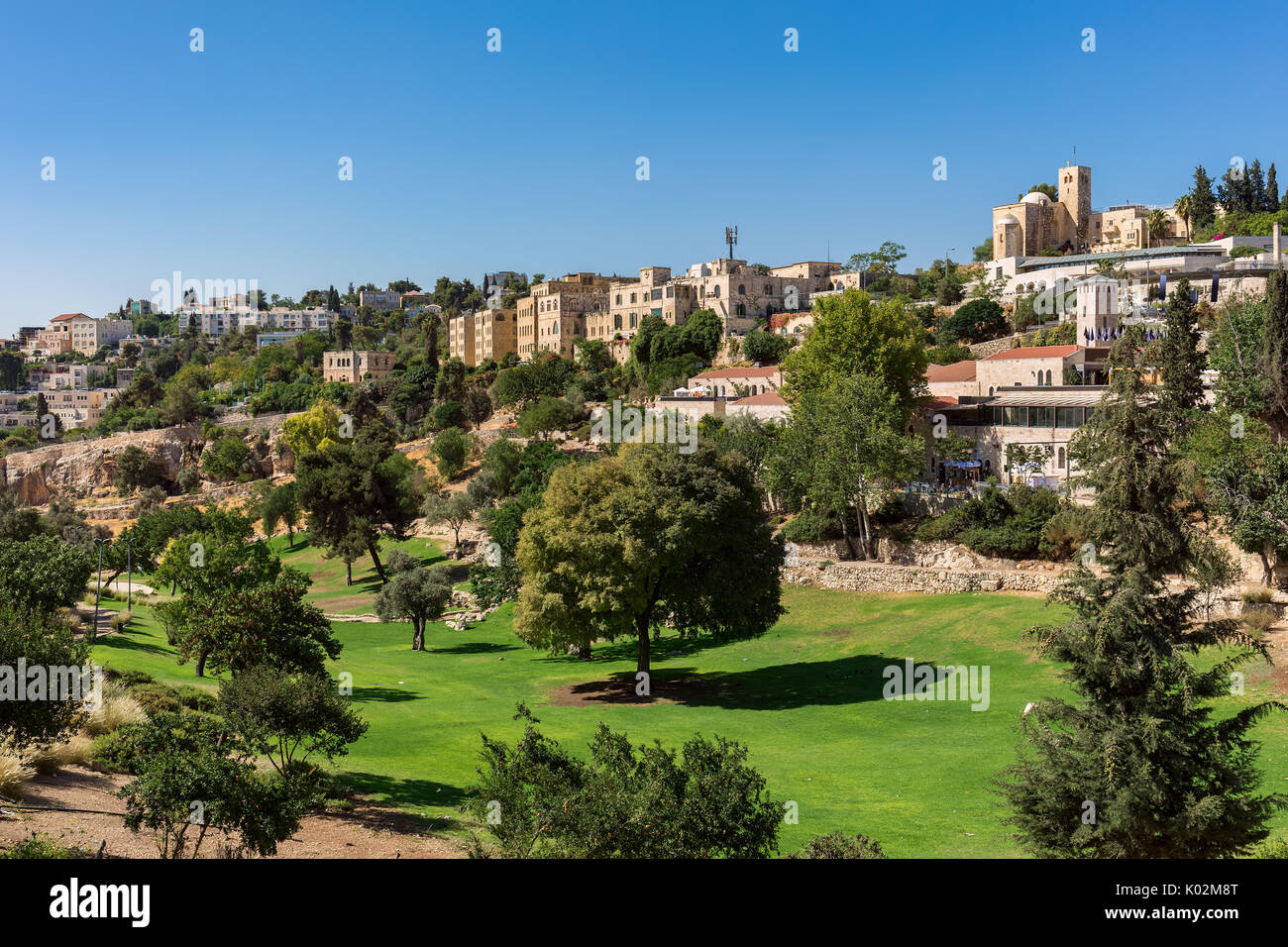 Vue sur pelouse verte et arbres de Zurich jardin comme arrière-plan sur les maisons typiques à Jérusalem, Israël. Banque D'Images