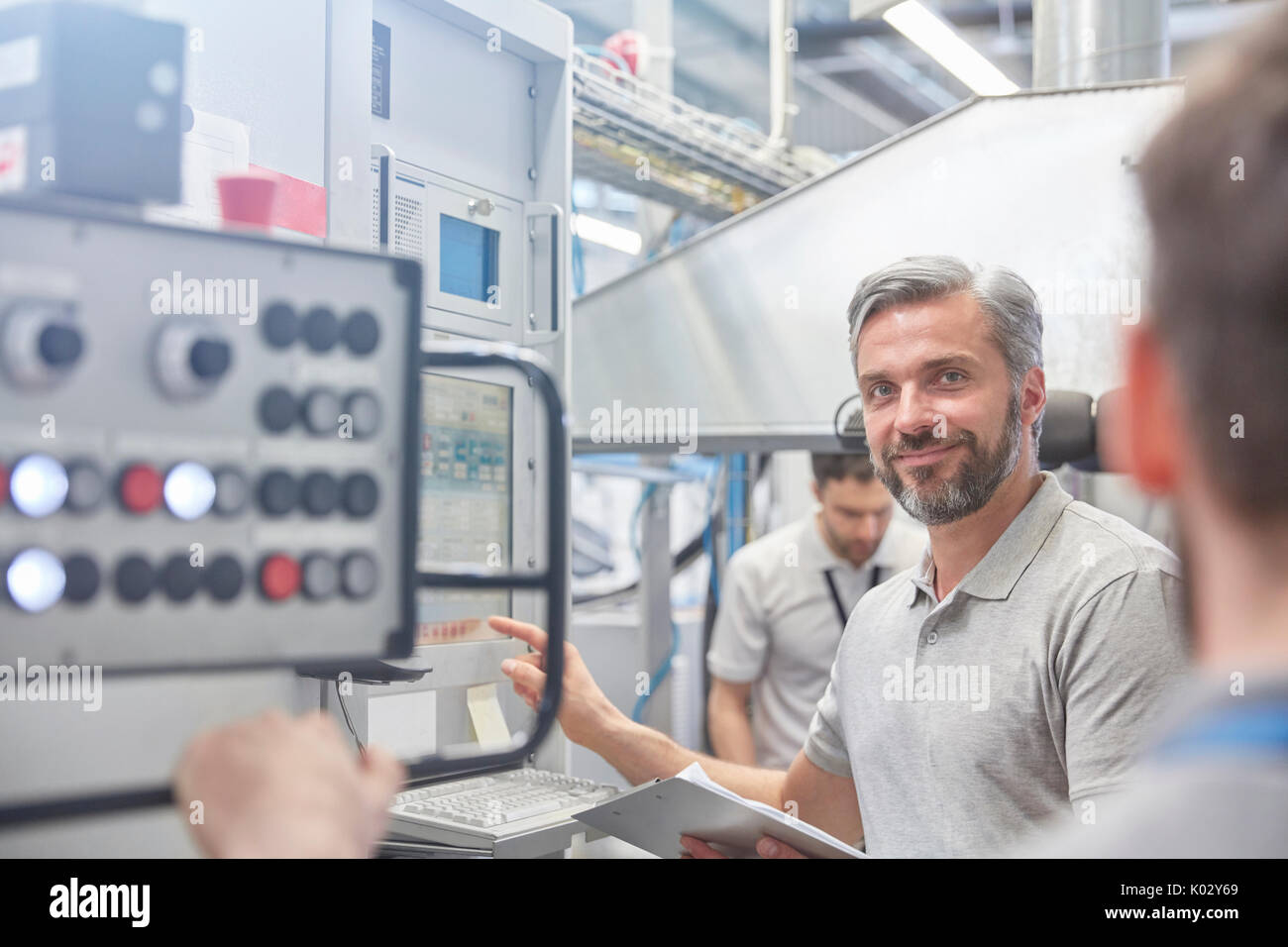 Portrait smiling male manager au panneau de commande de machines en usine Banque D'Images