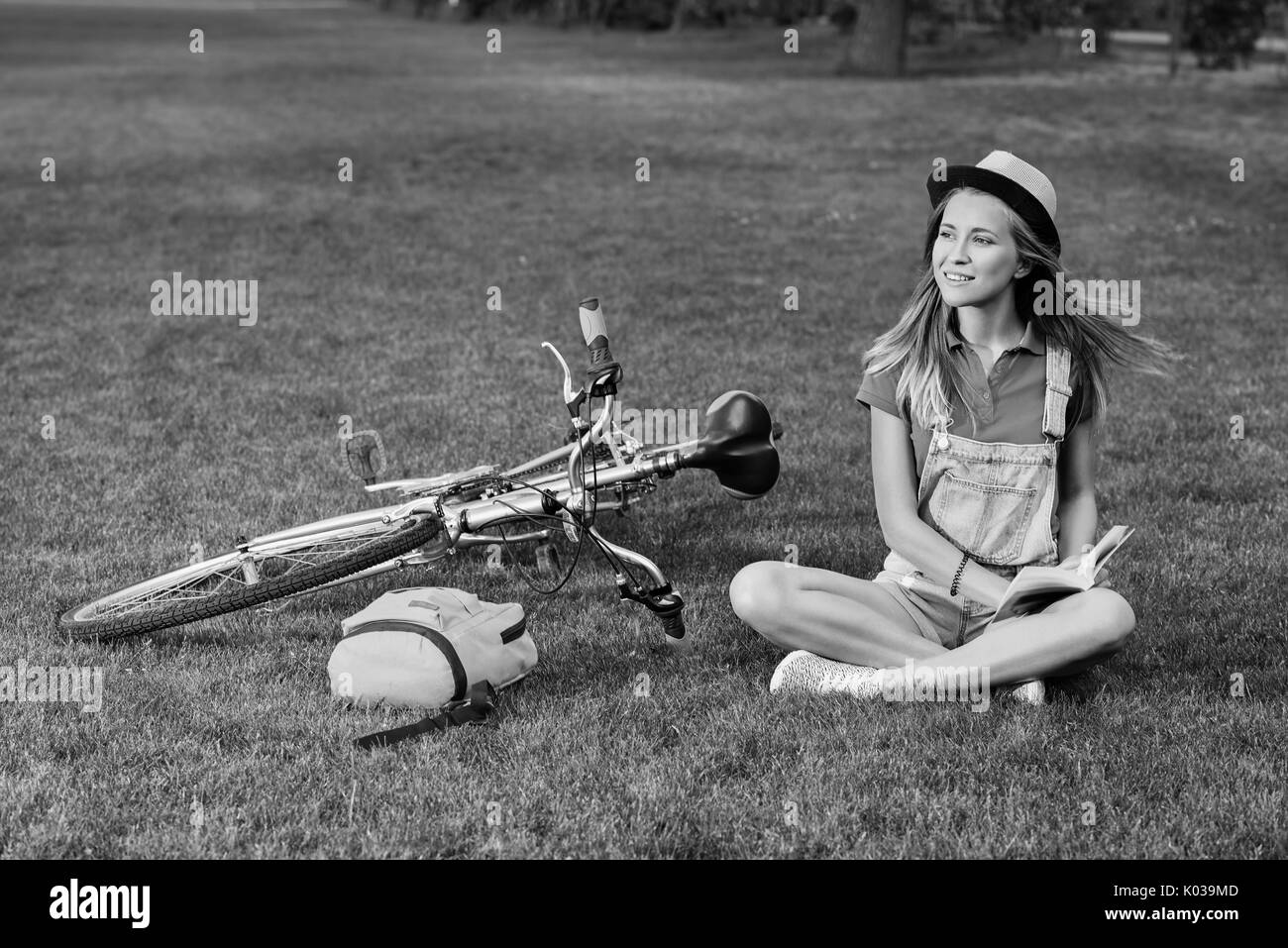 Jeune femme lisant un livre après le vélo à l'échelle locale park Banque D'Images