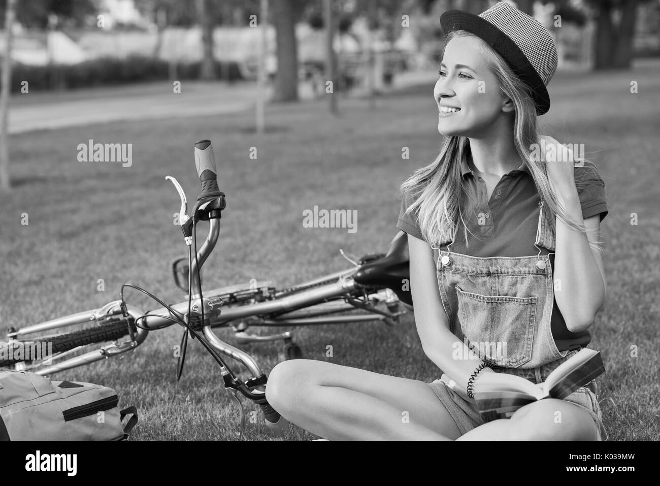Jeune femme lisant un livre après le vélo à l'échelle locale park Banque D'Images