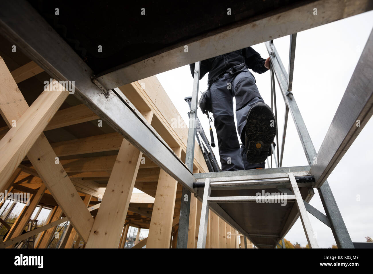 Male Carpenter en descente à l'échelle de construction incomplète Banque D'Images