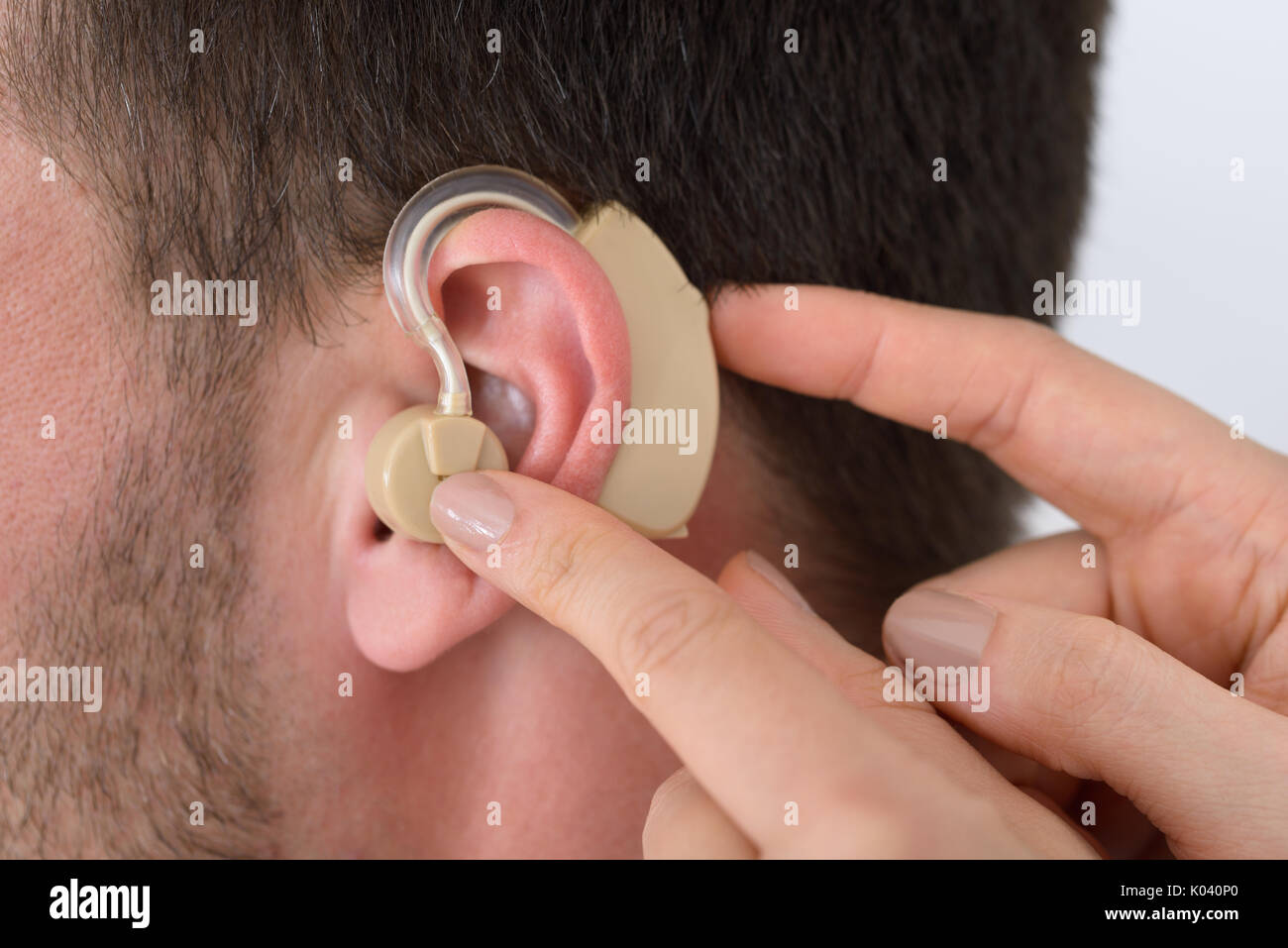 Close-up of main du médecin l'insertion d'un appareil auditif dans l'oreille  d'un homme Photo Stock - Alamy