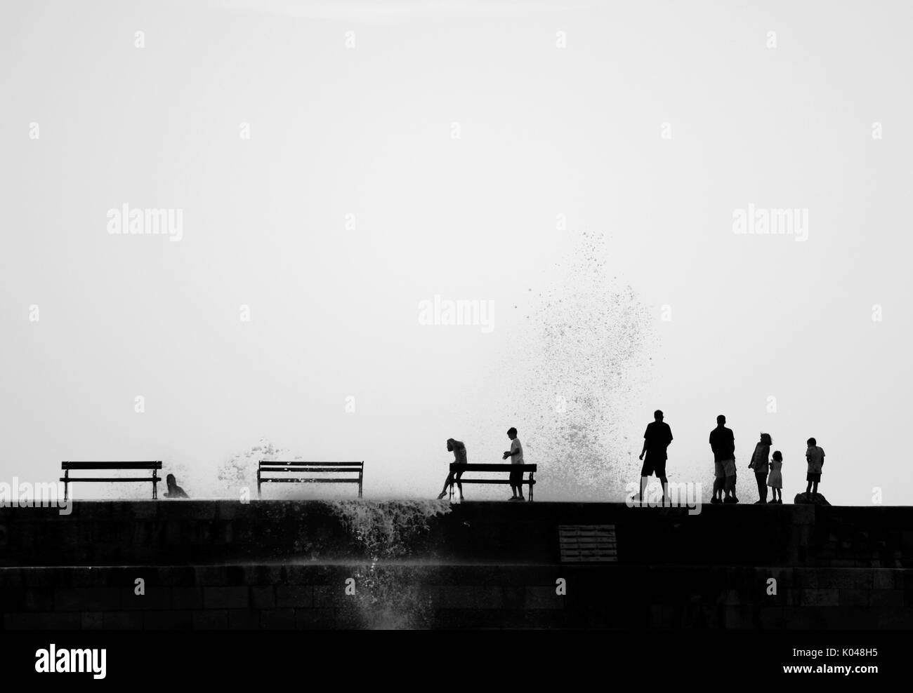 Silhouettes de personnes sur le brakewater, grosses vagues, aux projections d'eau, Porporela à Dubrovnik, Croatie Banque D'Images