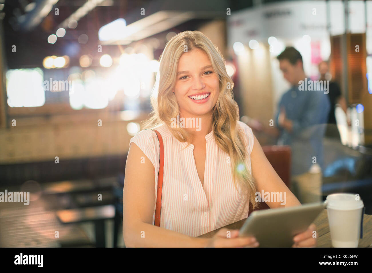 Portrait of smiling young woman using digital tablet at cafe Banque D'Images