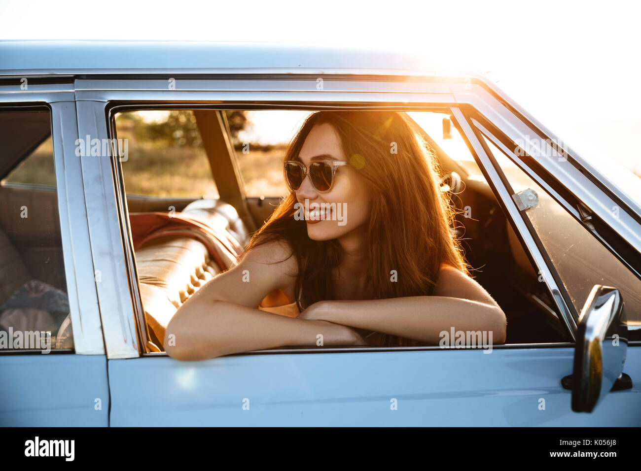 Smiling woman leaning on une fenêtre et à l'écart tout en étant assis à l'intérieur d'une voiture Banque D'Images