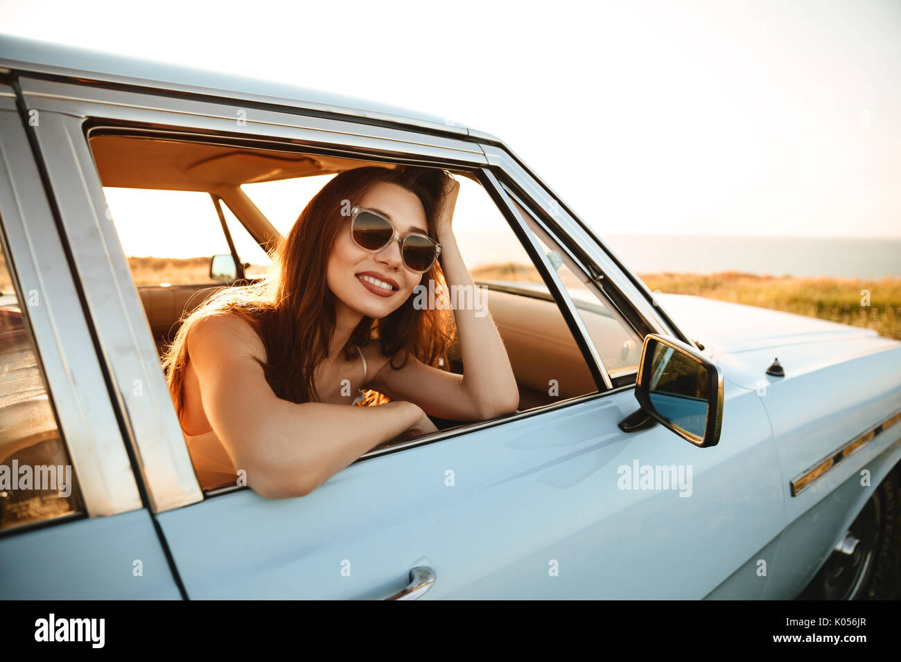 Happy woman leaning on une fenêtre et à l'écart tout en étant assis à l'intérieur d'une voiture Banque D'Images