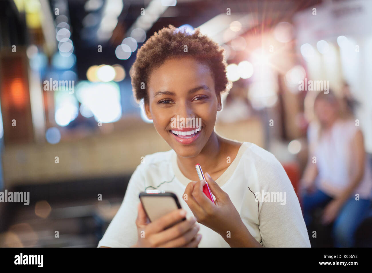Portrait of smiling young woman applying lipstick Banque D'Images
