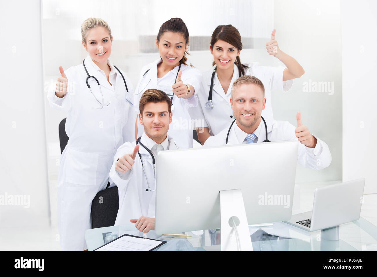 Portrait of confident doctors gesturing Thumbs up at desk in clinic Banque D'Images