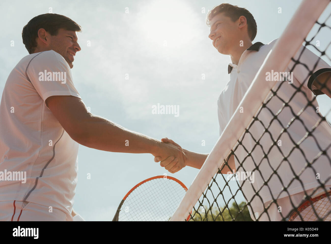 Les jeunes joueurs de tennis handshaking in esprit sportif au filet Banque D'Images