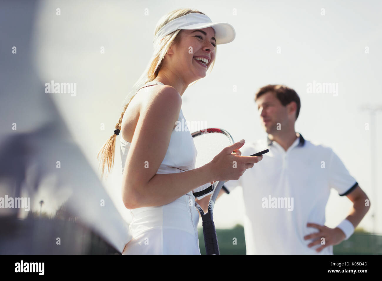 Rire tennis player holding cell phone et raquette de tennis Banque D'Images