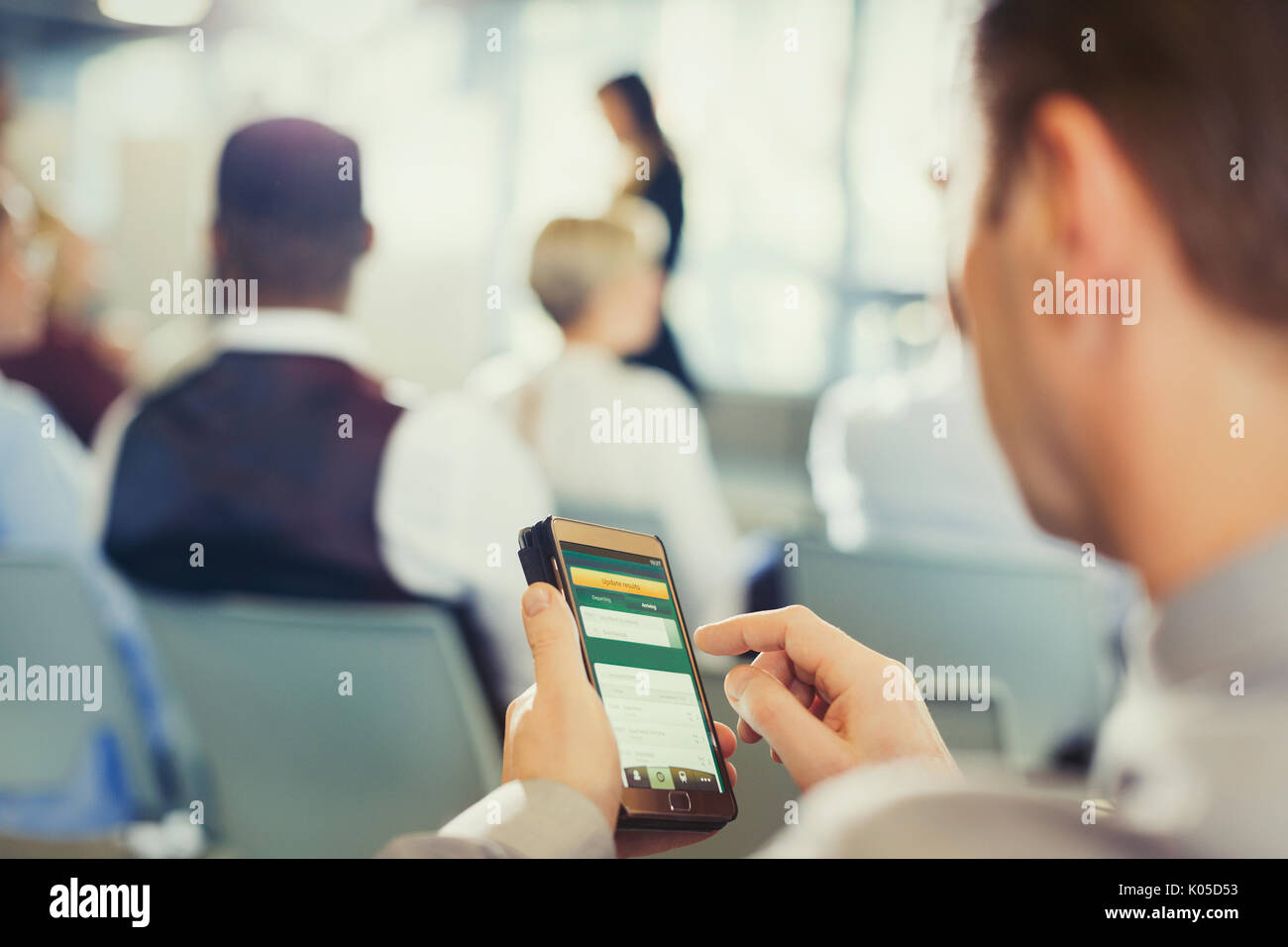 Businessman texting with cell phone in public conférence Banque D'Images