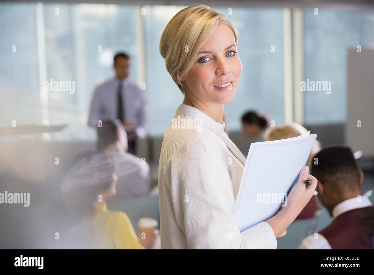 Portrait smiling businesswoman with paperwork dans la salle de conférence réunion Banque D'Images
