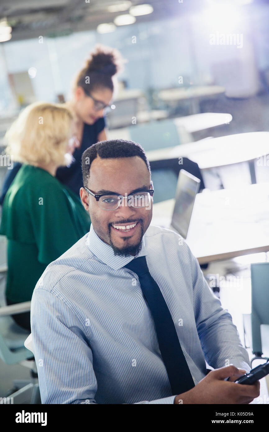 Portrait of smiling businessman texting with cell phone in office Banque D'Images