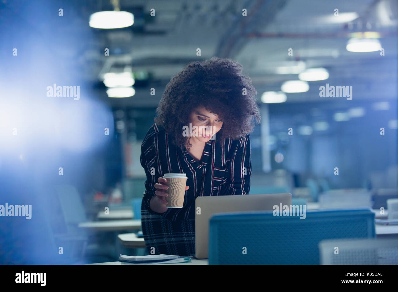 Businesswoman travailler tard le coffre, de boire du café dans le bureau sombre Banque D'Images