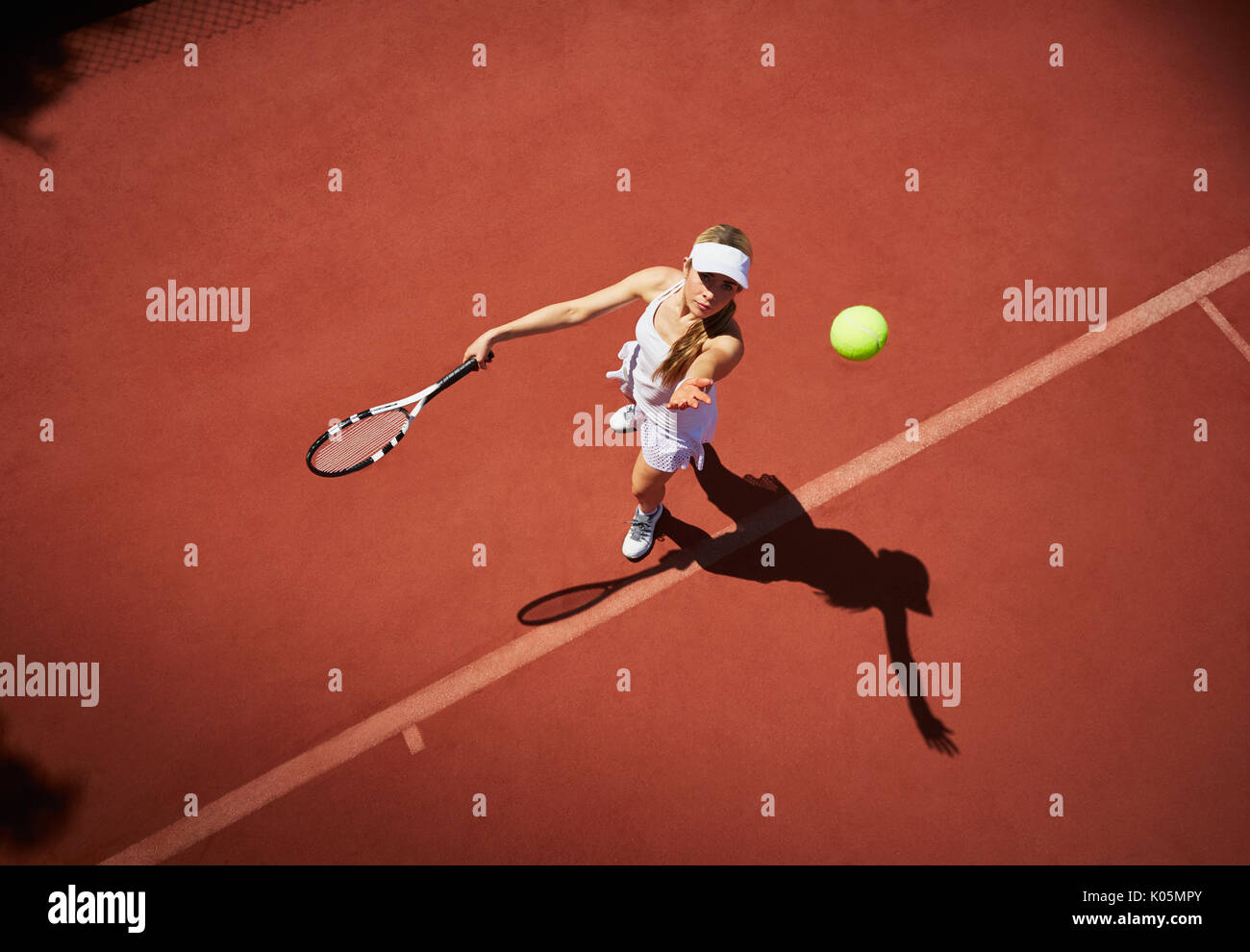 Vue aérienne du jeune joueur de tennis féminin à jouer au tennis, au service de la balle de tennis au soleil Banque D'Images