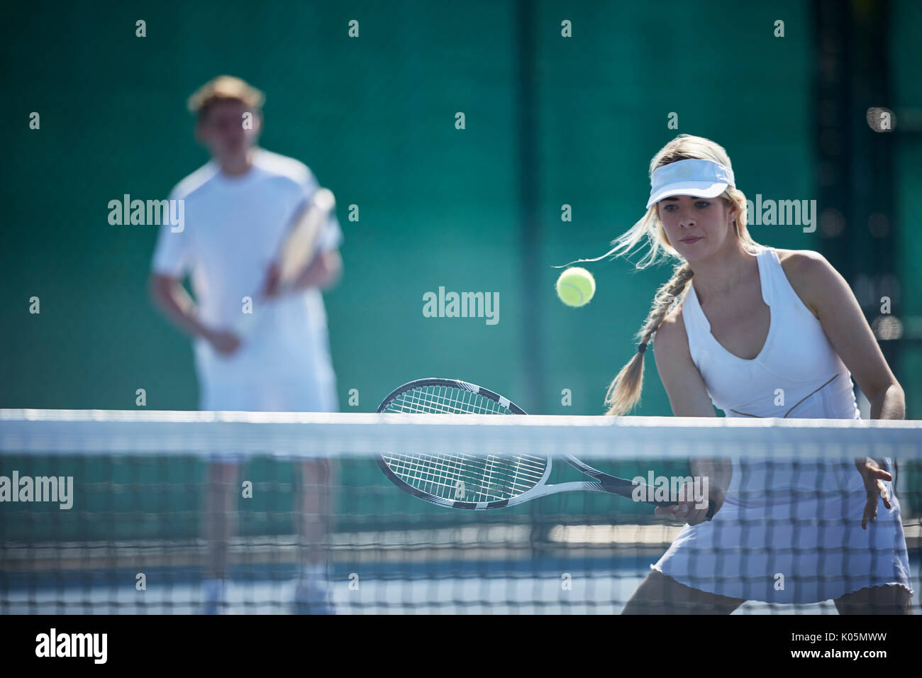 Tennis player jeune et déterminé à jouer au tennis, frapper la balle de tennis sur le court de tennis ensoleillé net Banque D'Images