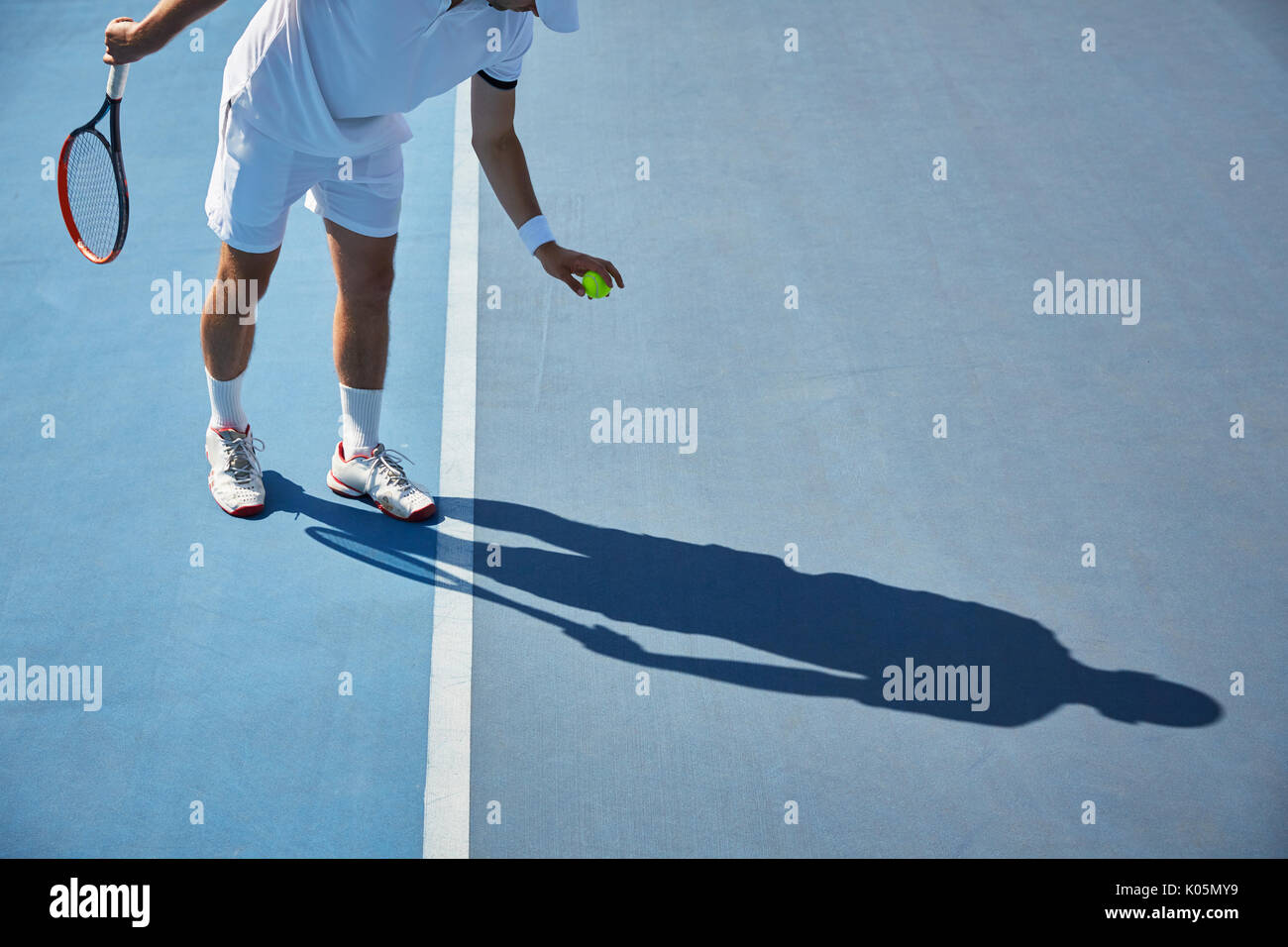 Jeune joueur de tennis masculin en jouant au tennis, balle de tennis qui rebondit sur sunny blue tennis Banque D'Images