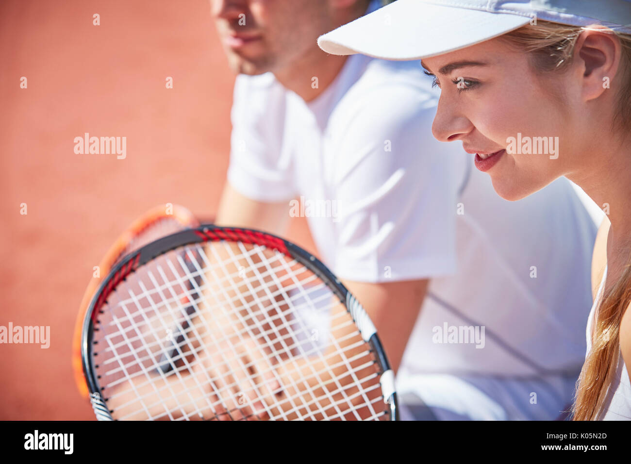 Souriant, confiant young woman playing tennis doubles, prêt avec raquette de tennis Banque D'Images