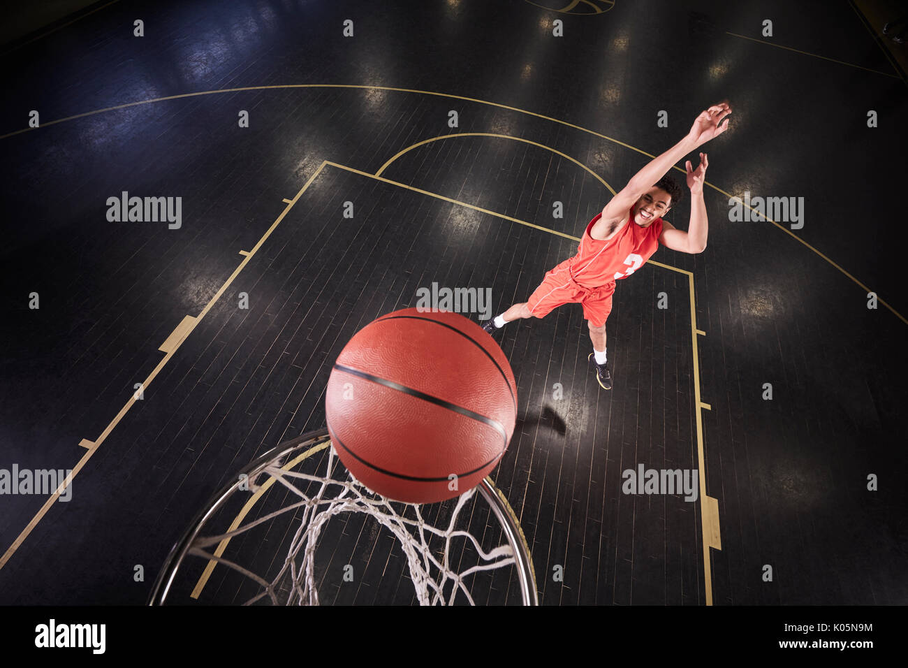 Jeune joueur de basket-ball masculin le tir de la balle sur le court in gymnasium Banque D'Images