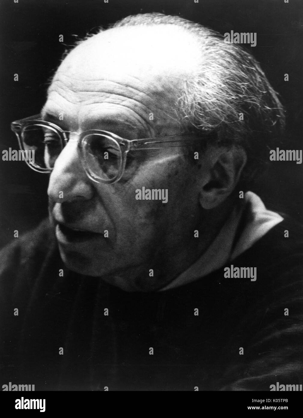 Head-shot portrait du compositeur et écrivain Aaron Copland, avec d'épais verres clairs, avec une expression du visage sérieux, regardant vers le bas face à sa droite, 1975. Banque D'Images