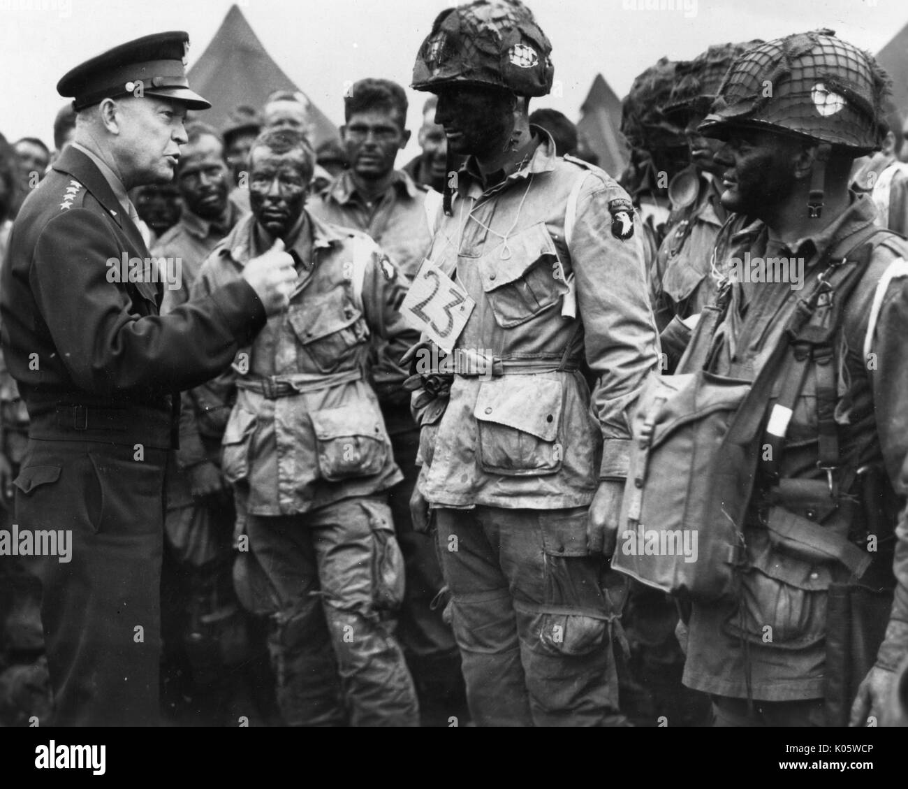Portrait du général Dwight D. Eisenhower commandant ses soldats à l'extérieur d'un camp, Eisenhower dans un noir uniforme militaire, et les soldats en vêtements militaires échevelée avec la peinture pour le visage et des casques, des expressions faciales, 1945. Banque D'Images