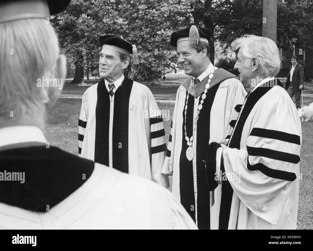 Trois-quarts portrait de trois hommes à l'Université Johns Hopkins, début 1980 Photo prise sur l'épaule d'un autre homme, les expressions du visage souriant, debout sur un campus quad, wearing cap and Gown, de gauche à droite : Daniel K Ludwig, Steven Muller, et le compositeur et pianiste américain Leonard Bernstein, 1980. Banque D'Images