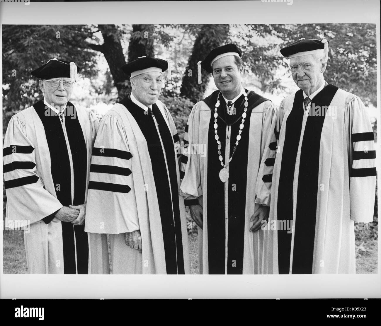 Portrait de trois-quarts de trois professeurs de l'Université Johns Hopkins et le président, debout dans des robes et chapeaux au jour dit, en face d'un arbre, avec des expressions du visage souriant, de gauche à droite : Ralph Edward Gibson, Edgar AJ Johnson, président Steven Muller, Don Cameron et Allen, 1975. Banque D'Images