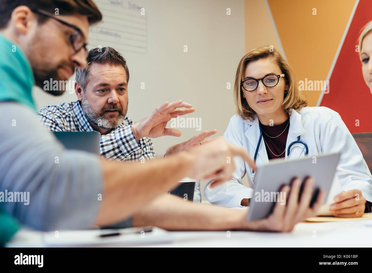 Groupe des travailleurs de la santé avec tablette numérique dans la salle de réunion de l'hôpital. Le personnel médical au cours d'information du matin. Banque D'Images