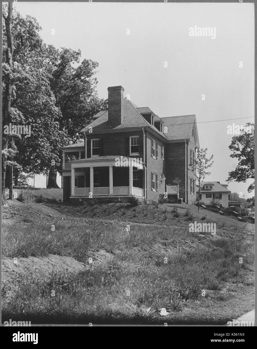 Portrait d'une maison de trois étages sur une zone herbeuse inclinée, avec un porche blanc, une cheminée, et entouré d'arbres avec des feuilles, Roland Park/Guilford, United States, 1910. Cette image est tirée d'une série sur la construction et la vente de maisons dans le quartier Roland Park/Guilford de Baltimore, a streetcar suburb et l'une des premières communautés planifiées aux États-Unis. Banque D'Images
