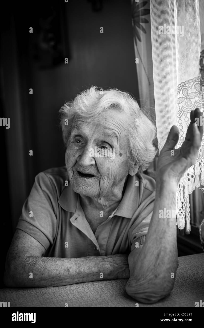 Portrait noir et blanc d'une vieille femme qui parle dans la chambre. Banque D'Images