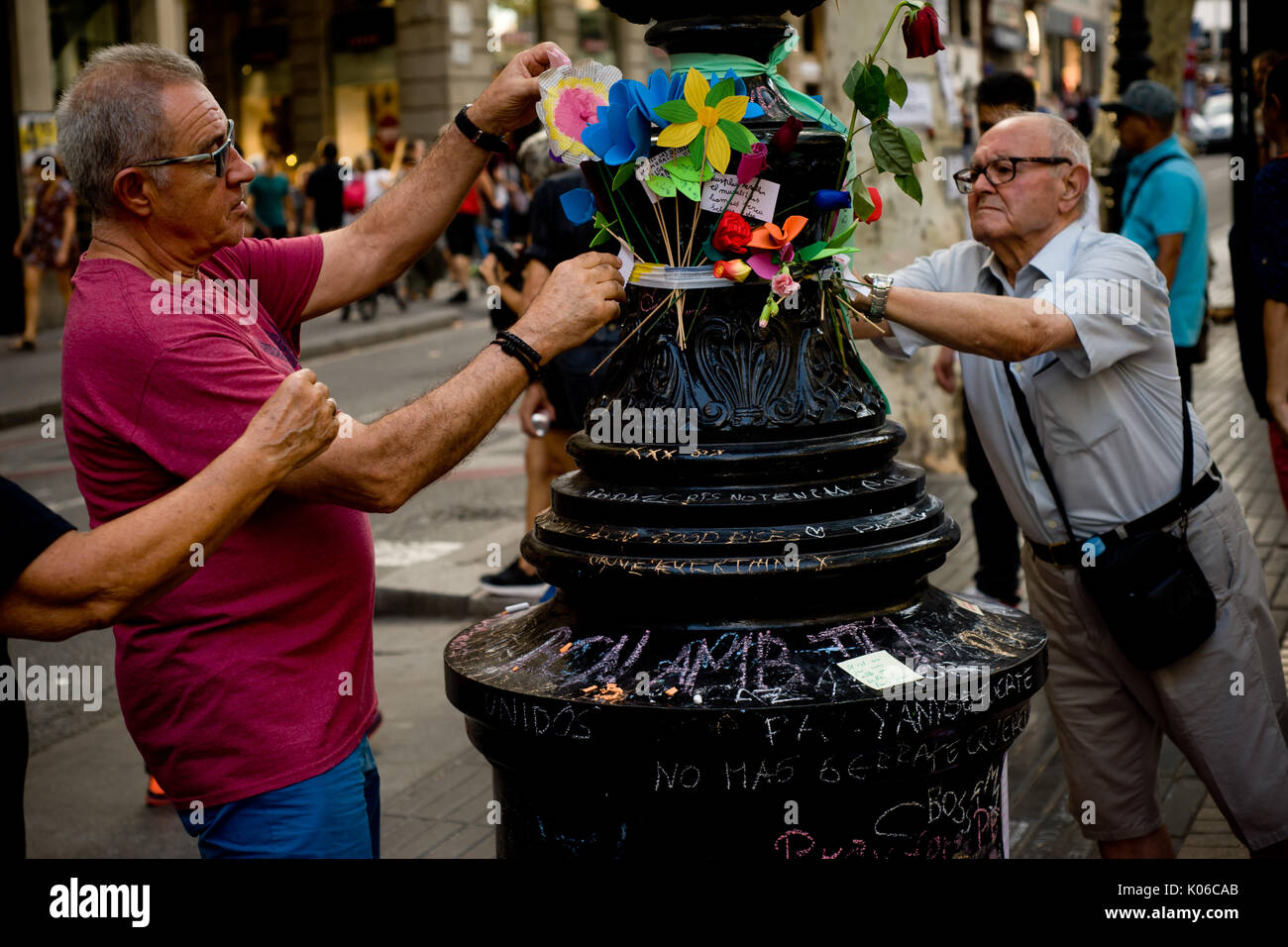 Barcelone, Espagne. Août 21, 2017. Deux hommes place fleurs à un lampadaire de Las Ramblas de Barcelone, en mémoire de l'attaque terroriste aux victimes le même jour que Younes Abouyaaqoub, identifiés comme chauffeur de van qui a accéléré le long de la rue Las Ramblas le jeudi, a été abattu par des agents de police catalane dans le village de Subirats. Crédit : Jordi Boixareu/Alamy Live News Banque D'Images