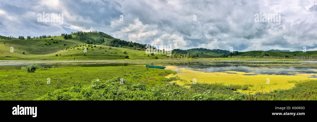 Lac incroyable dans vallée de montagnes avec des algues et de lis blancs couverts - Vue panoramique du paysage d'été avec ciel nuageux et bateau sur la rive de l'étang, un Banque D'Images