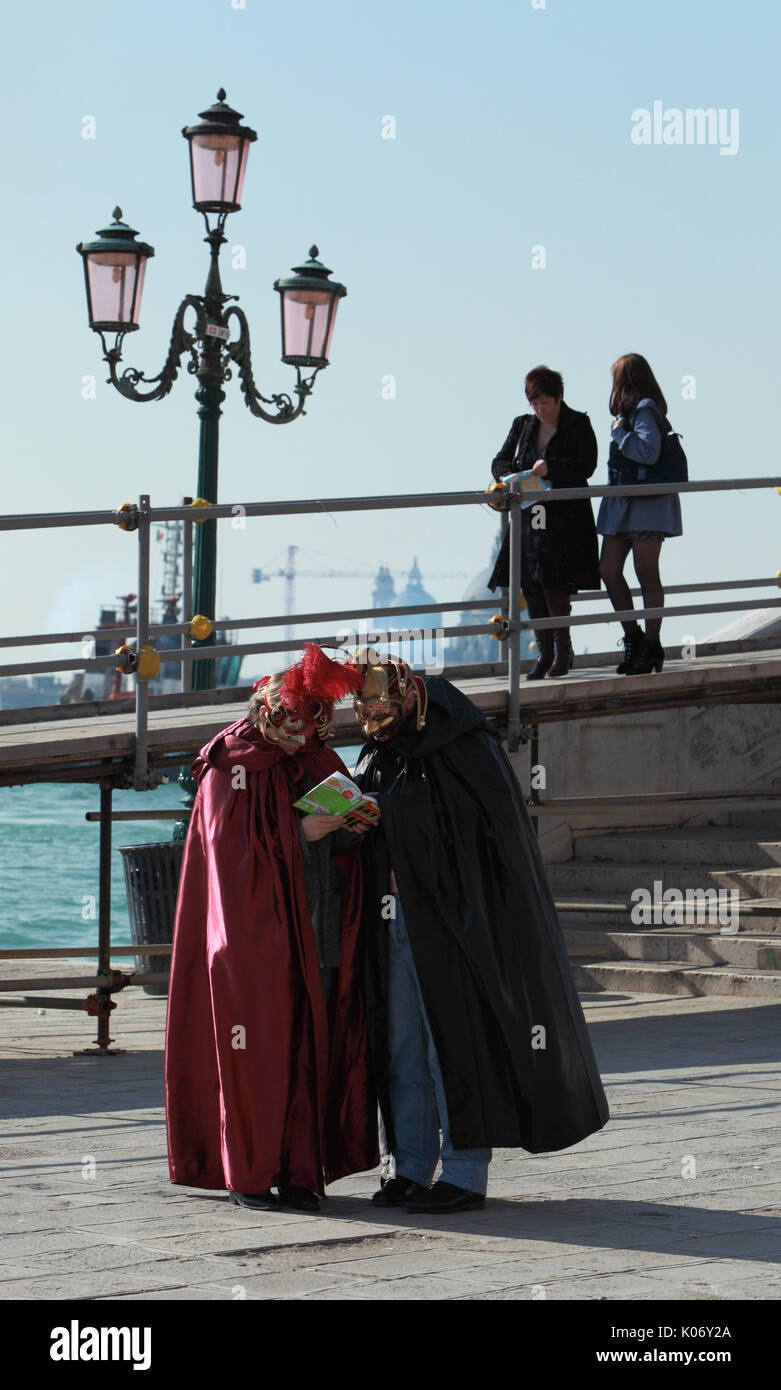 Venise, Italie - Février 26th, 2011 : Deux touristes déguisées en costumes vénitiens arrêtés et lu dans un guide de voyage sur Venise Sestiere Castello, pendant t Banque D'Images