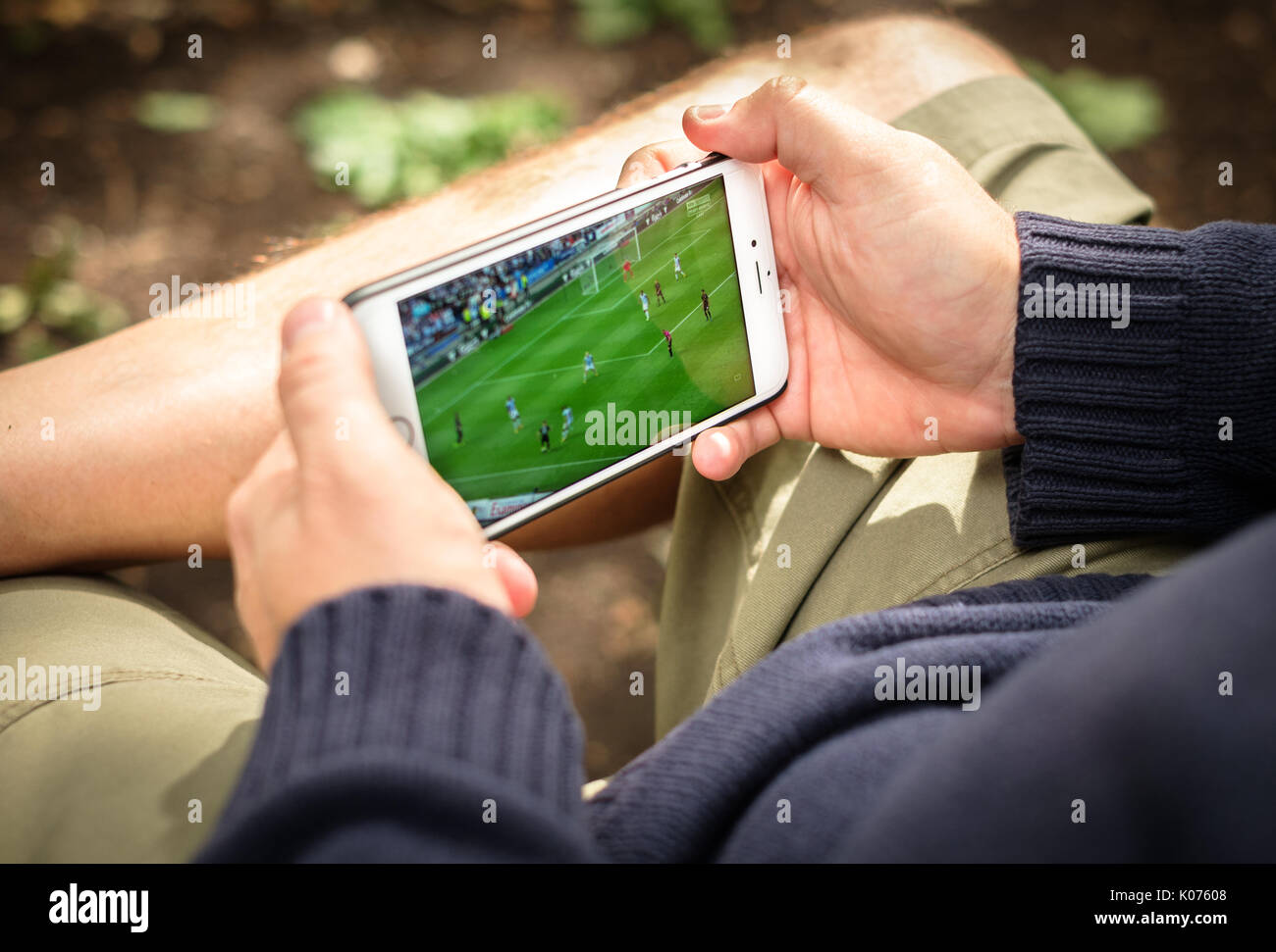 Homme qui regarde un match de football en streaming sur smartphone en zone rurale Banque D'Images