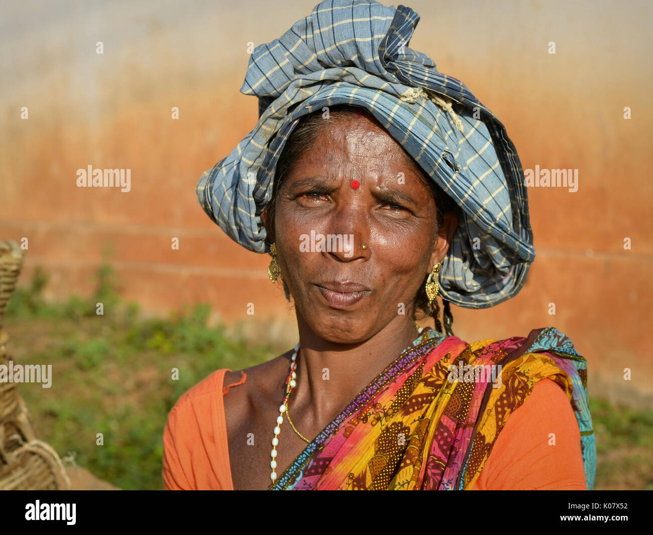 Femme indienne Adevasi avec de précieuses pendants d'oreilles dorés pose pour la caméra. Banque D'Images