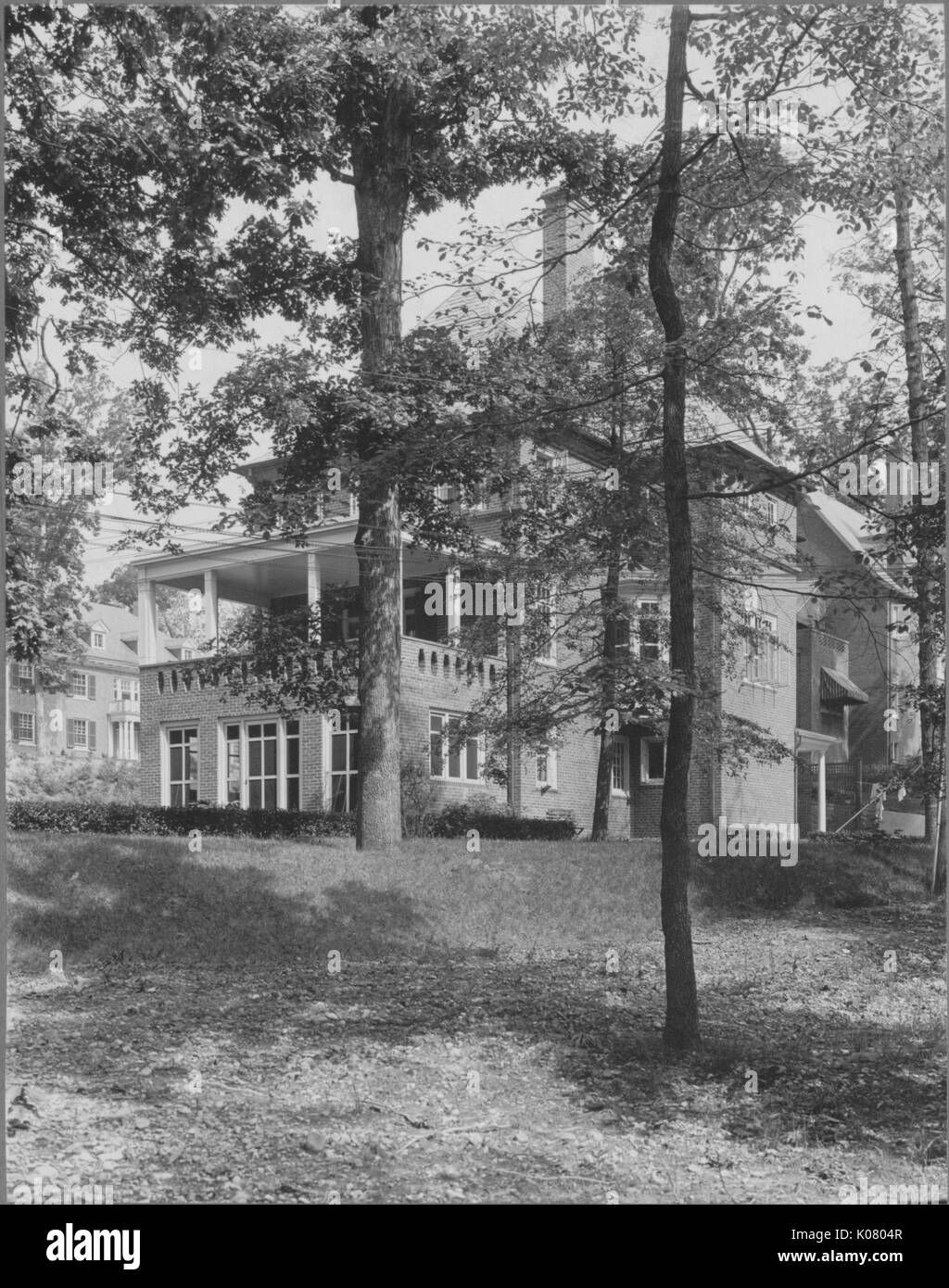 Vue avant de l'angle accueil dans environnement calme, couverte d'arbres, entouré d'herbe, semble être de trois étages avec porche sur second story, sur la colline légèrement surélevée avec des pas sur le côté, à côté d'une autre chambre, United States, 1910. Cette image est tirée d'une série sur la construction et la vente de maisons dans le quartier Roland Park/Guilford de Baltimore, a streetcar suburb et l'une des premières communautés planifiées aux États-Unis. Banque D'Images