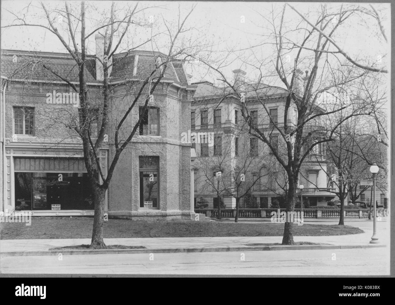 Deux bâtiments, le bâtiment sur la gauche avec deux étages et une grande fenêtre sur la première histoire, la taille des fenêtres à l'étage, cheminée, bâtiment à droite derrière le bâtiment à gauche avec quatre étages, de nombreuses fenêtres, et d'une balustrade entourant la zone avant ; deux arbres sans feuilles, et d'un réverbère devant le bâtiment de gauche ; Roland Park/Guilford, 1910. Cette image est tirée d'une série sur la construction et la vente de maisons dans le quartier Roland Park/Guilford de Baltimore, a streetcar suburb et l'une des premières communautés planifiées aux États-Unis. Banque D'Images