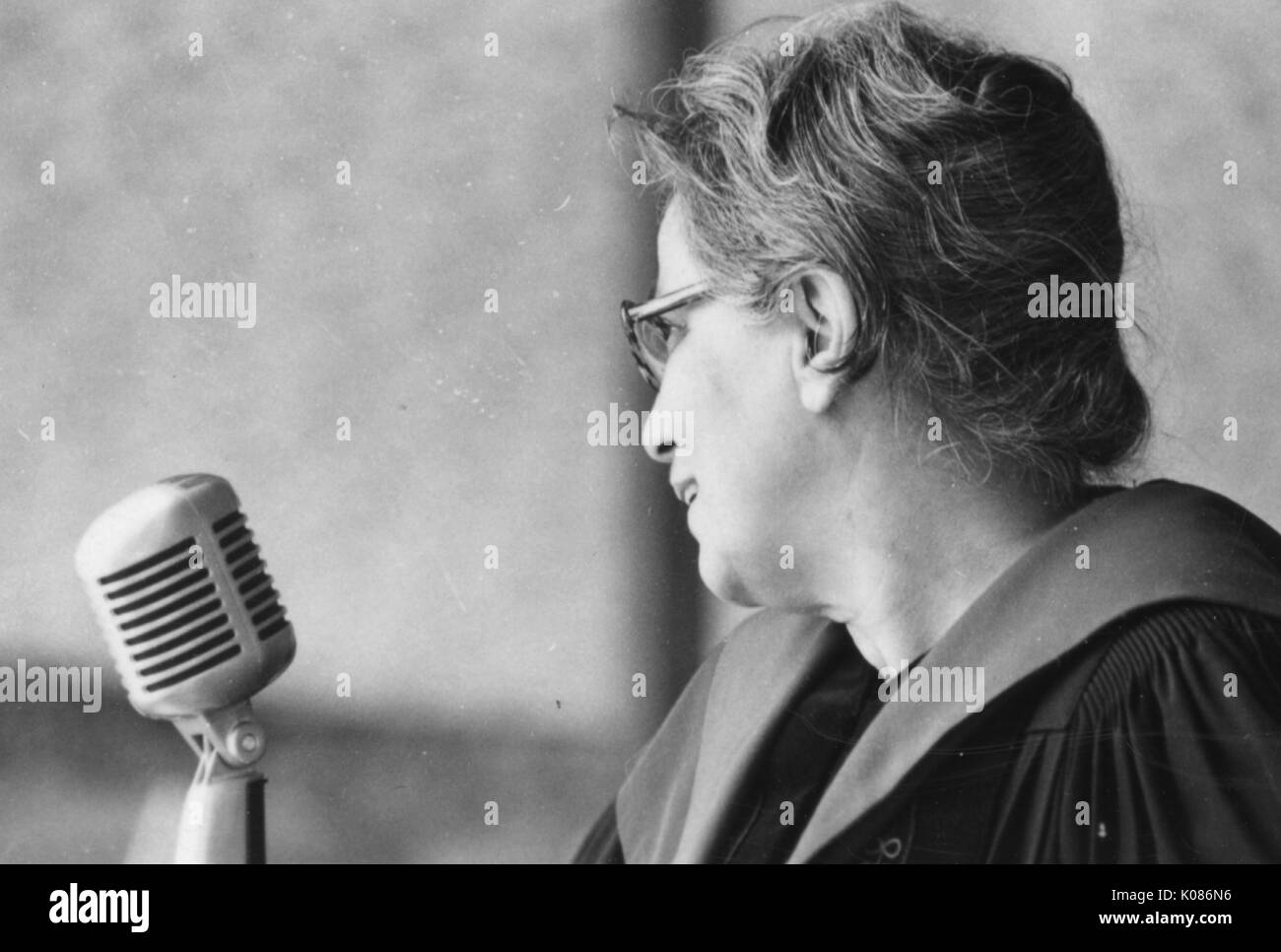 Universitaire féminin sourit en elle parle dans un micro, le port de lunettes et robe universitaire, sur le campus de l'Homewood de l'Université Johns Hopkins à Baltimore, Maryland, 1971. Banque D'Images