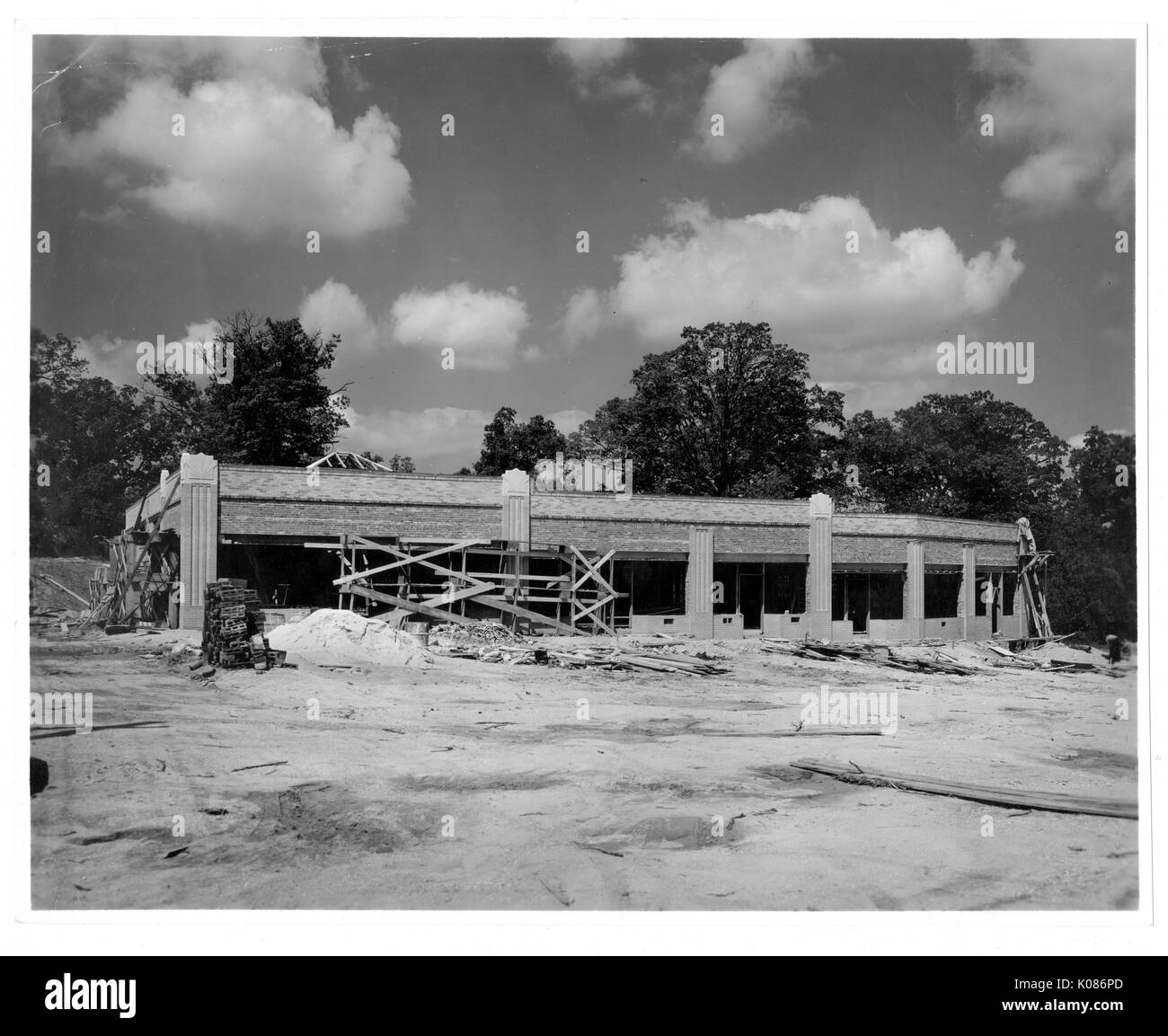 Bâtiment de Baltimore Roland Park en construction, entouré de nombreux arbres, abattu lors d'une journée ensoleillée, tas de bois autour de l'édifice, et tas de terre autour de la structure, Baltimore, Maryland, 1920. Banque D'Images