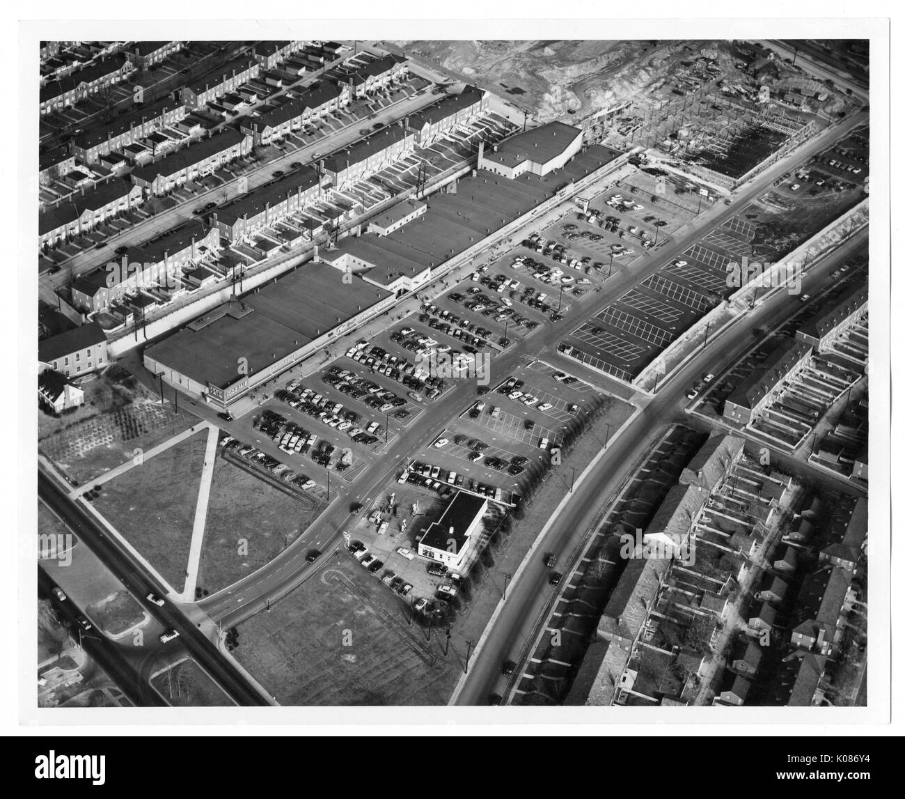 Bird's Eye View of Baltimore shot à partir de centaines de pieds au-dessus, d'un parking rempli de voitures, de nombreuses maisons de rangée, et certains champs d'herbe éparse en vue, Baltimore, Maryland, 1951. Banque D'Images