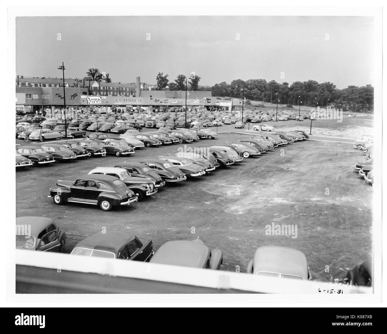 Vue d'un terrain de stationnement qui est emballé en construction, dans l'arrière-plan fait partie de la Northwood Shopping Centre et derrière le centre sont en rangée à gauche et les arbres à droite, Baltimore, Maryland, 1951. Banque D'Images