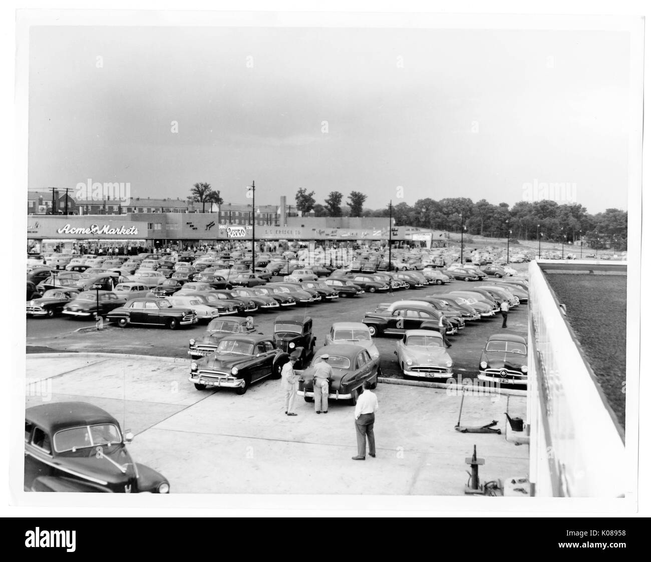 Vue d'un panier-parking et centre commercial du toit d'une station d'essence, plusieurs personnes sont debout à l'extérieur de la station service, à l'arrière-plan derrière le centre commercial sont en rangée et d'arbres, Baltimore, Maryland, 1951. Banque D'Images