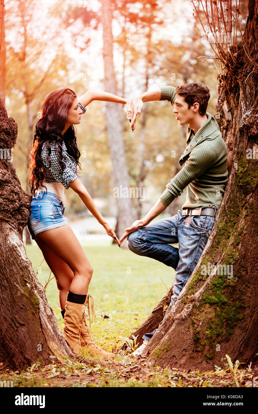 Belle lovely couple enjoying in sunny park en couleurs de l'automne et avec leurs mains en forme de coeur. Banque D'Images