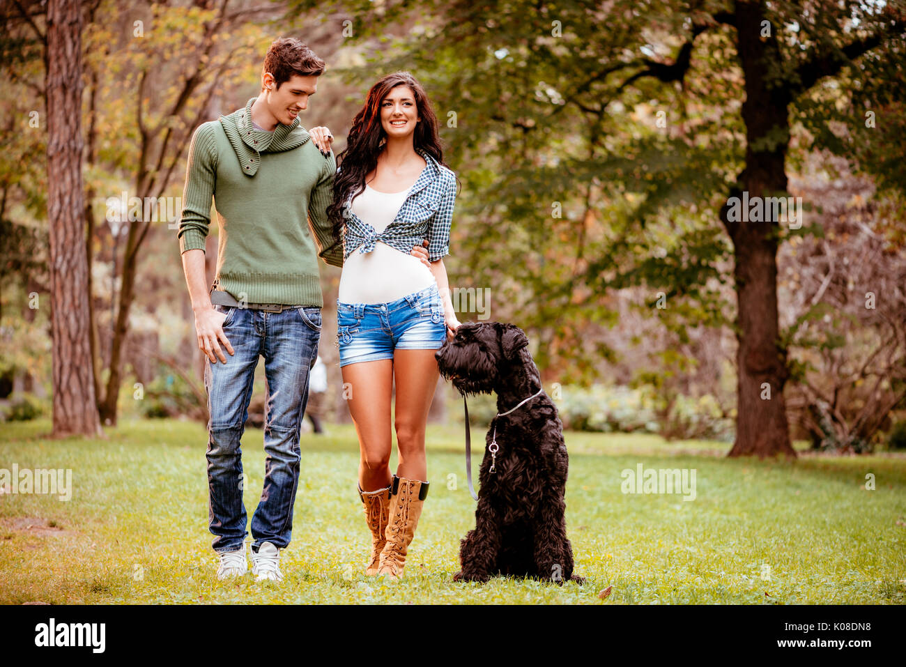Belle quel beau couple avec un Schnauzer Géant Noir, à les apprécier et à marcher dans le parc. Banque D'Images