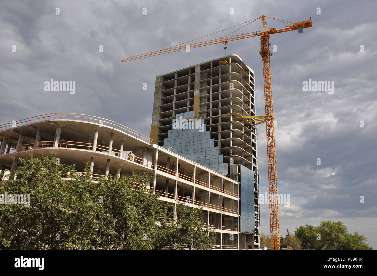 Site de construction d'une grue sur un gratte-ciel spectaculaire contre ciel nuageux. Banque D'Images