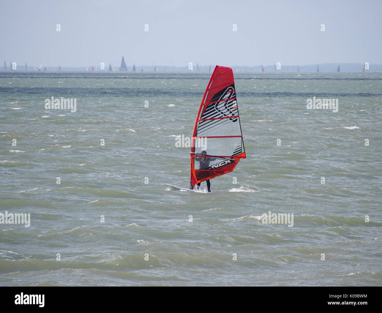 Un surfeur vent voiles sur le solent et l'île de Wight en arrière-plan. Banque D'Images