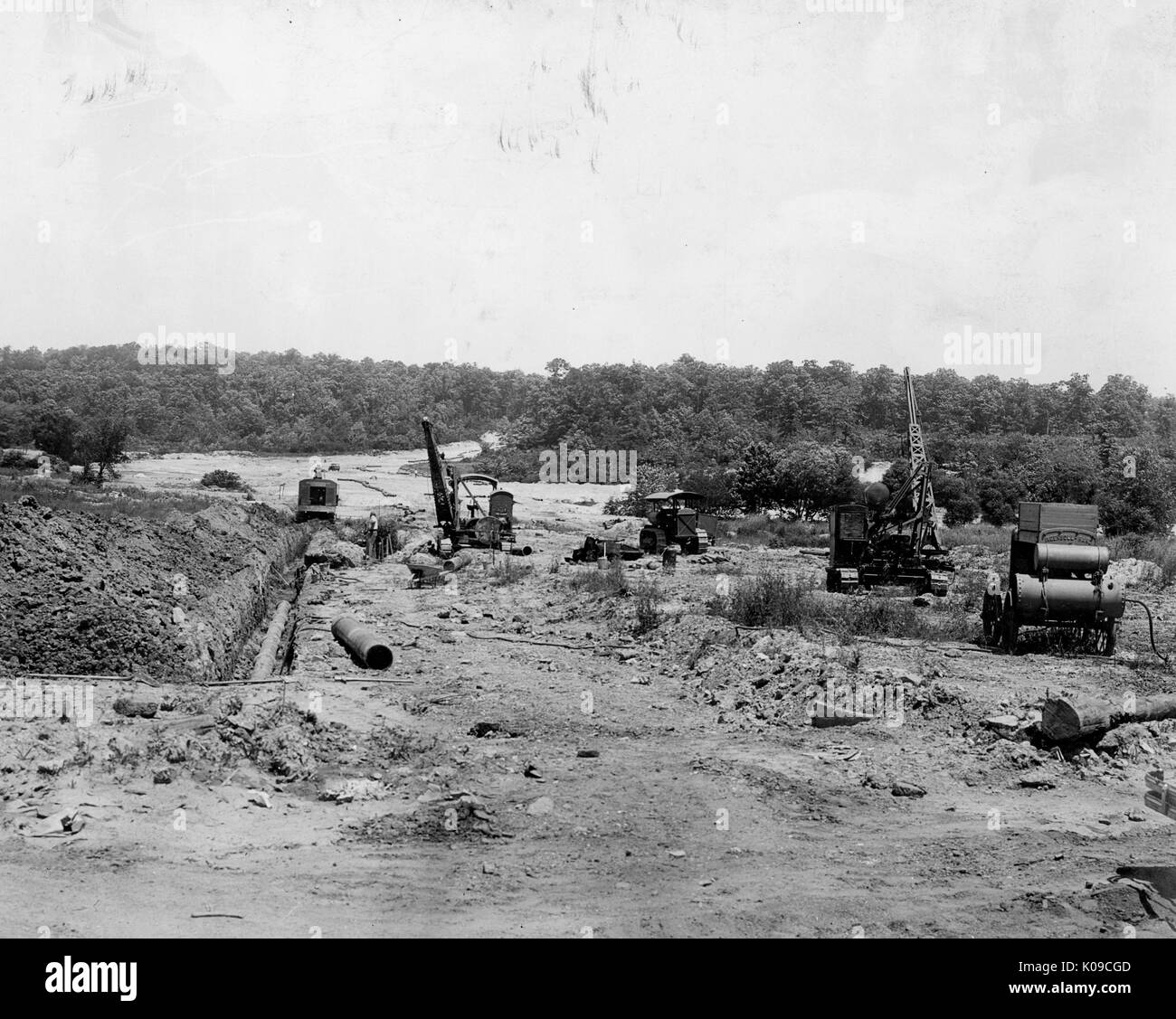 Paysage de terre Northwood en construction, il y a au moins quatre gros morceaux de matériel de construction sur le site et les arbres bordent le fond, United States, 1950. Banque D'Images