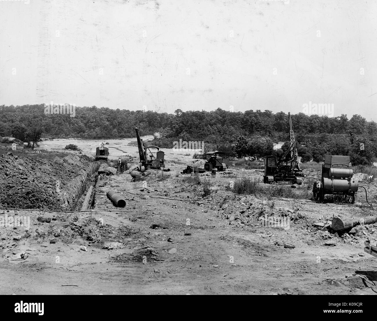 Paysage de terre Northwood en construction, il y a au moins quatre gros morceaux de matériel de construction sur le site et les arbres boarder l'arrière-plan, United States, 1950. Banque D'Images